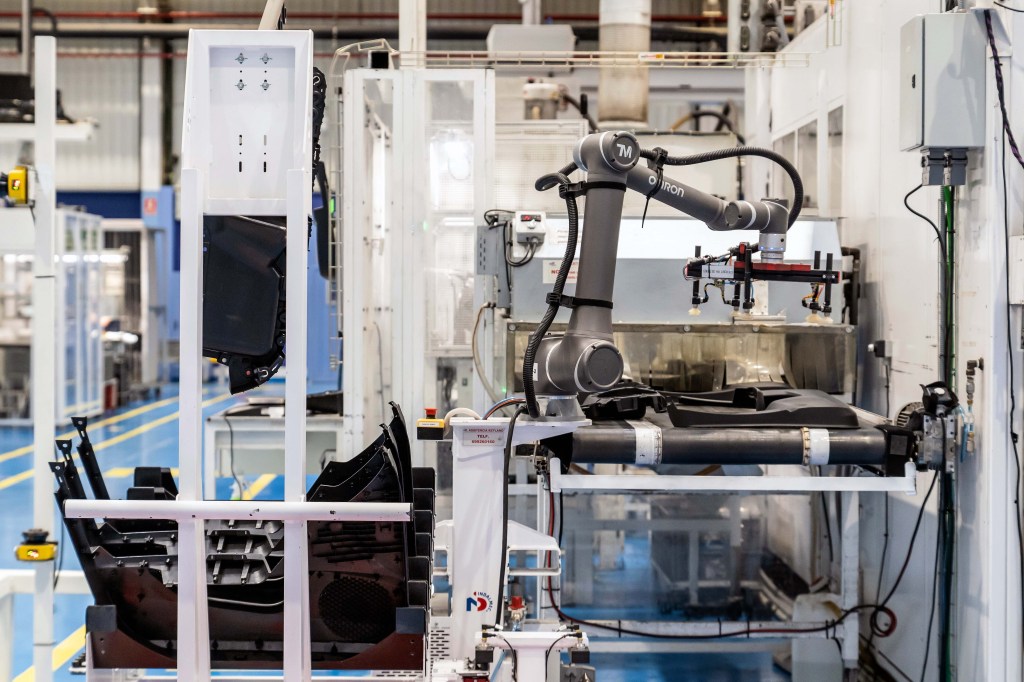 Automotive manufacturing automation with robotic arms assembling components