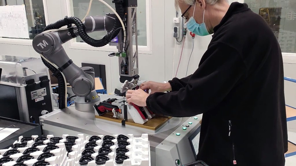 Operator collaborating with OMRON cobot for assembly automation in electric shaver manufacturing