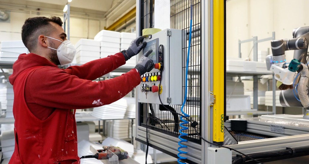 Operator overseeing cobot finishing cell as safety scanner pauses motion