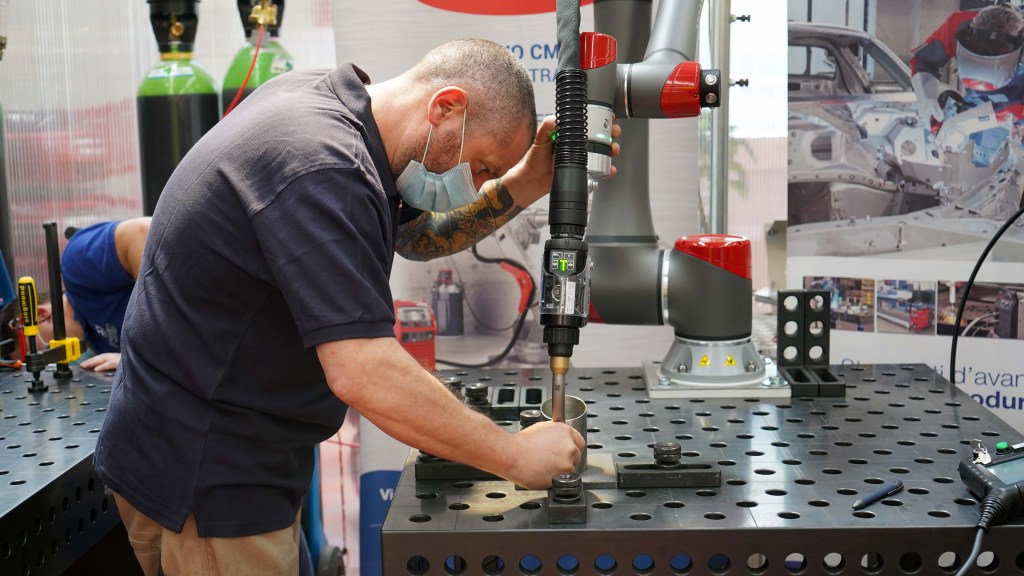 Operator working with automated welding cobot