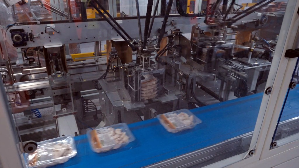 Food containers being stacked by automated packaging system