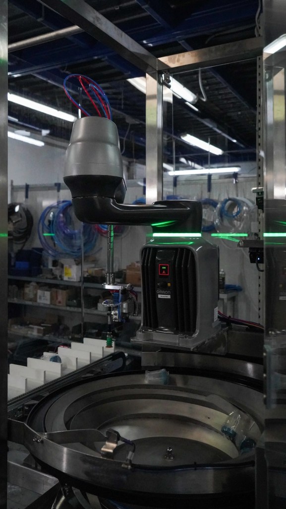 OMRON i4H SCARA robot positioned above circular feeder in a robotic end-of-line packaging system