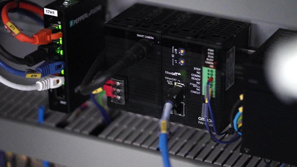 OMRON smart camera and industrial communication hardware inside a robotic packaging cell