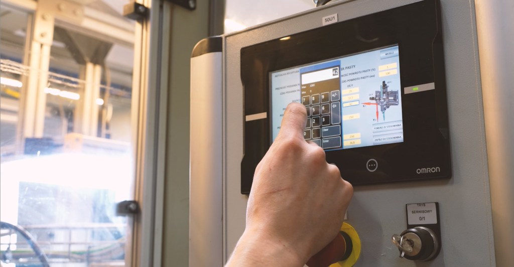 Bediener nutzt das OMRON HMI zur Anpassung der Maschineneinstellungen
